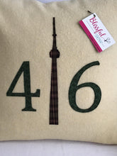 Load image into Gallery viewer, Cream colored pillow with green numbers and check CN Tower.
