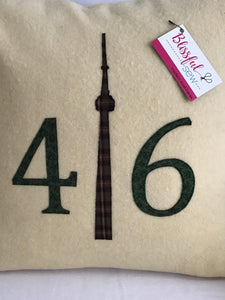 Cream colored pillow with green numbers and check CN Tower.
