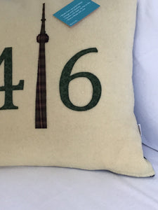 Cream colored pillow with green numbers and check CN Tower.