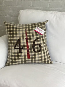 Cream pillow with chocolate brown squares with cranberry plaid numbers and CN Tower.