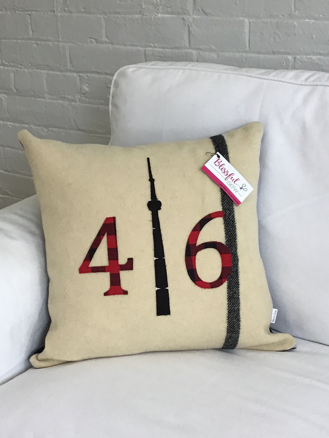 Felted Wool Blanket Pillow - Cream colored background with solid black stripe up the side.  Red plaid numbers and black CN Tower.