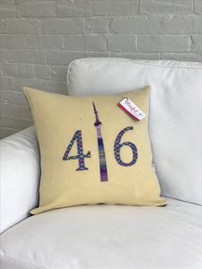 Cream colored pillow with purple, lime, pink numbers and batik CN Tower.